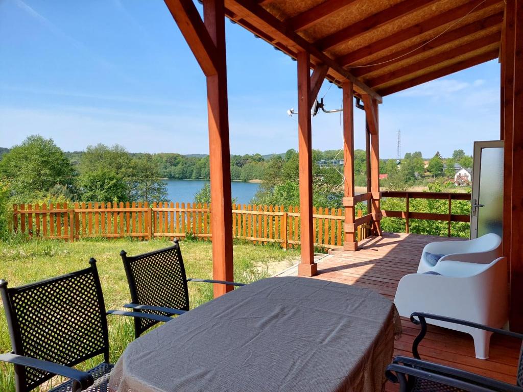 a porch with a table and chairs and a view of a lake at Domus Mare domek holenderski in Wisełka