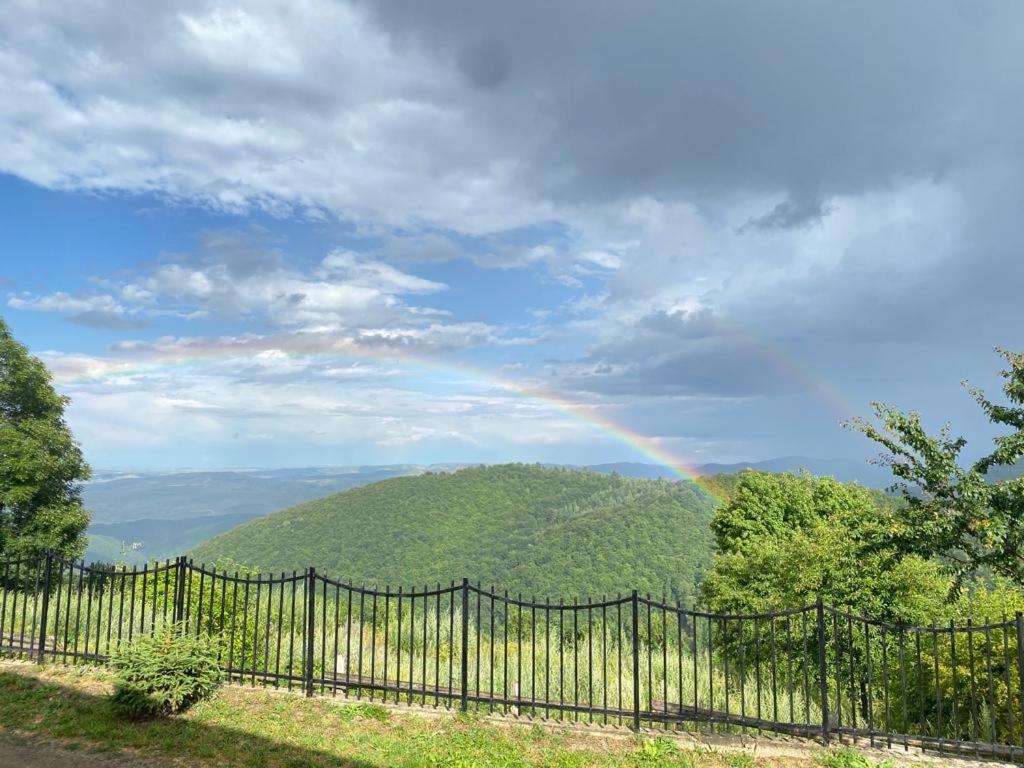 a rainbow over a hill with a fence at Cabana Refugiu Montan in Băişoara