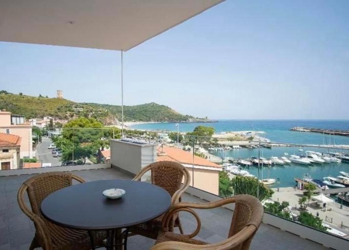 a table and chairs on a balcony with a view of a harbor at Hotel La Scogliera in Marina di Camerota