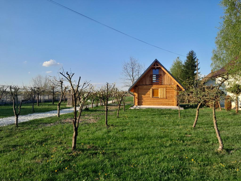 una cabaña de madera en un campo con árboles en Drewniany Domek Małgorzatka, 