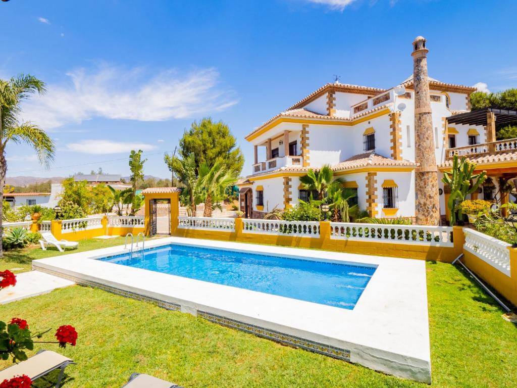 a villa with a swimming pool in front of a house at Cubo's Villa Fina & Minigolf included in Málaga
