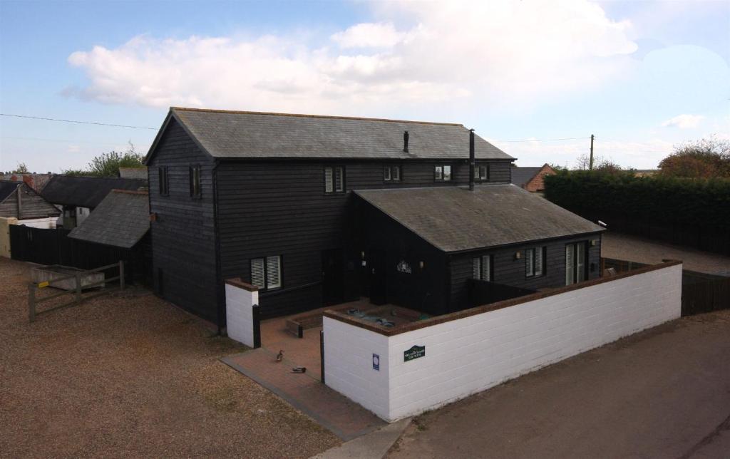 a black house with a white wall next to it at The Cart Lodge at Lee Wick Farm Cottages & Glamping in Saint Osyth