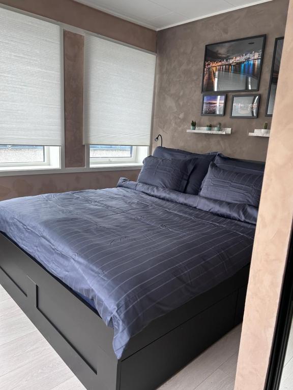 um quarto com uma cama com lençóis azuis e janelas em MK8 Apartment em Bergen