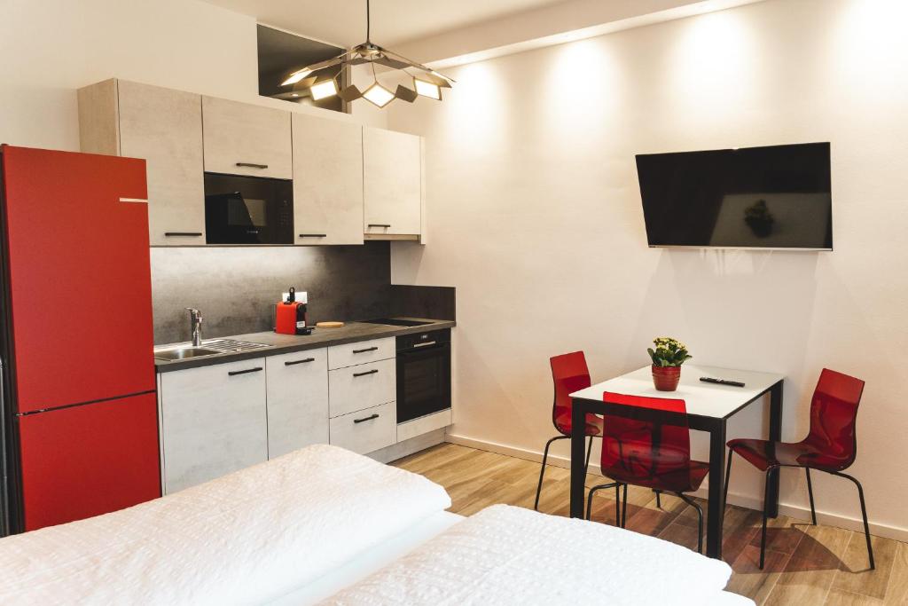 cocina con nevera roja y mesa con sillas en Lux - Studio-Appartment, en Merano