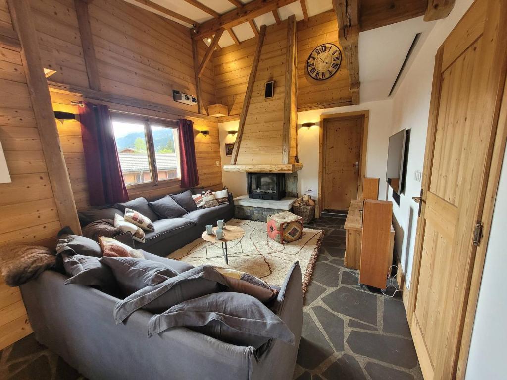 - un salon avec des canapés et une horloge murale dans l'établissement Chalet familial aux Gets, proche pistes, 4 chambres, cheminée et Wifi - FR-1-598-35, aux Gets