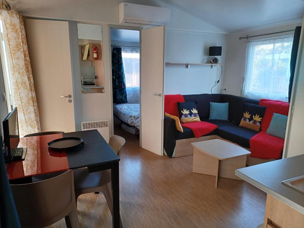 a living room with a couch and a table at Le Cosy, mobil-home 4-6 personnes au camping les Sables du Midi à Valras-Plage in Valras-Plage