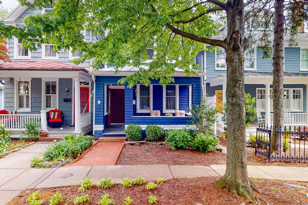 a blue house with a red door and a tree at Seas The Bay in Annapolis