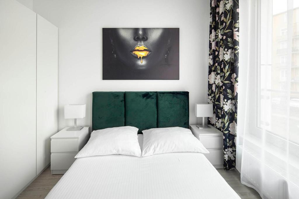 een slaapkamer met een wit bed met een groen hoofdeinde bij Sleepy3city Plac Unii in Gdynia
