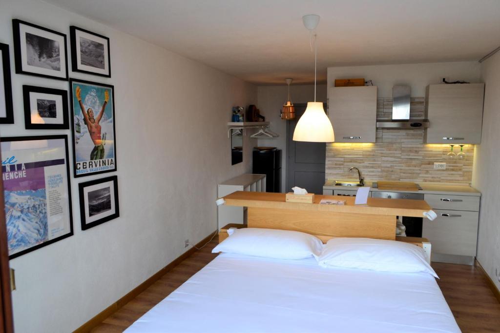 a bedroom with a white bed and a kitchen at Mountain Studio 109A in Breuil-Cervinia