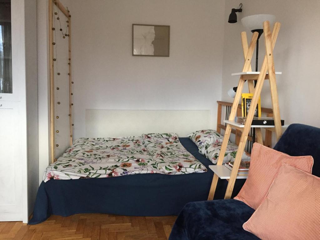 a bedroom with a bed and a ladder next to a chair at Sunny Studio blisko plaży in Sopot