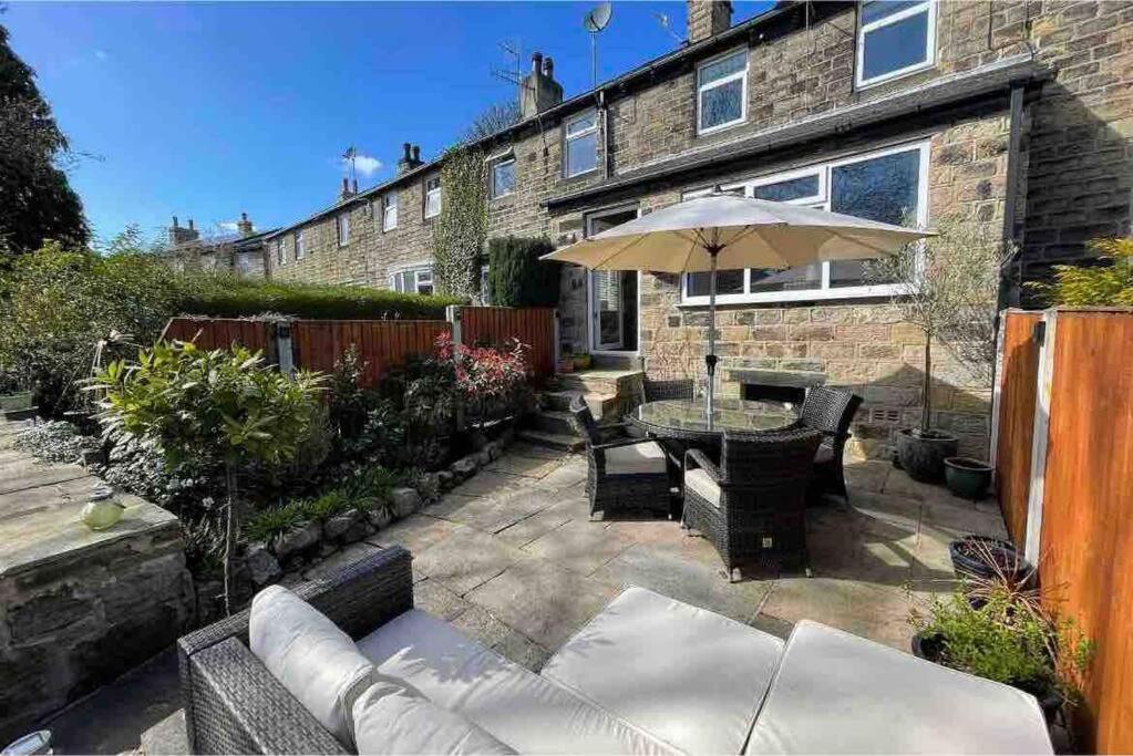 a patio with a table and an umbrella at Brook Cottage in the heart of Yorkshire in Baildon