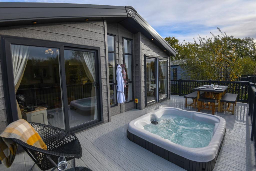 a jacuzzi tub on a deck next to a house at Lakewood retreat in Woodhall Spa