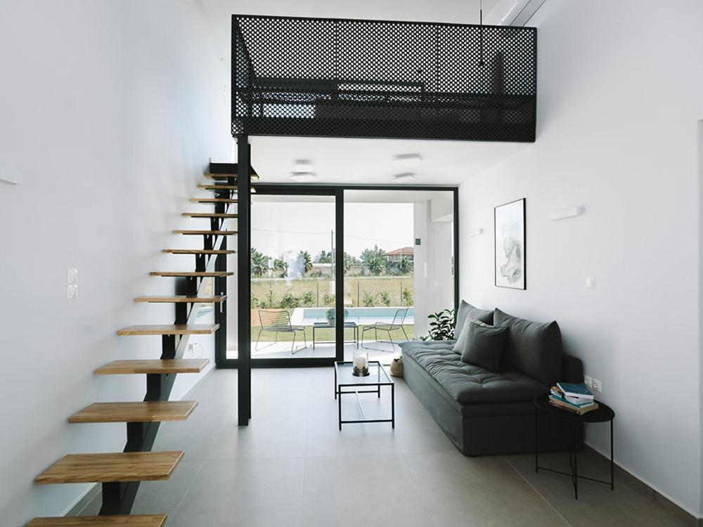 - un salon avec un canapé et un escalier en colimaçon dans l'établissement Sevene Villas, à Petroúlai