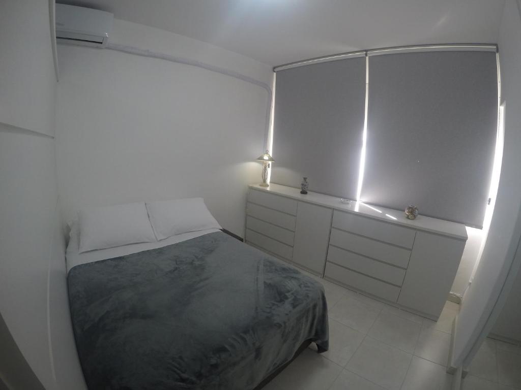 a white bedroom with a bed and a mirror at Ap no centro de Florianopolis in Florianópolis