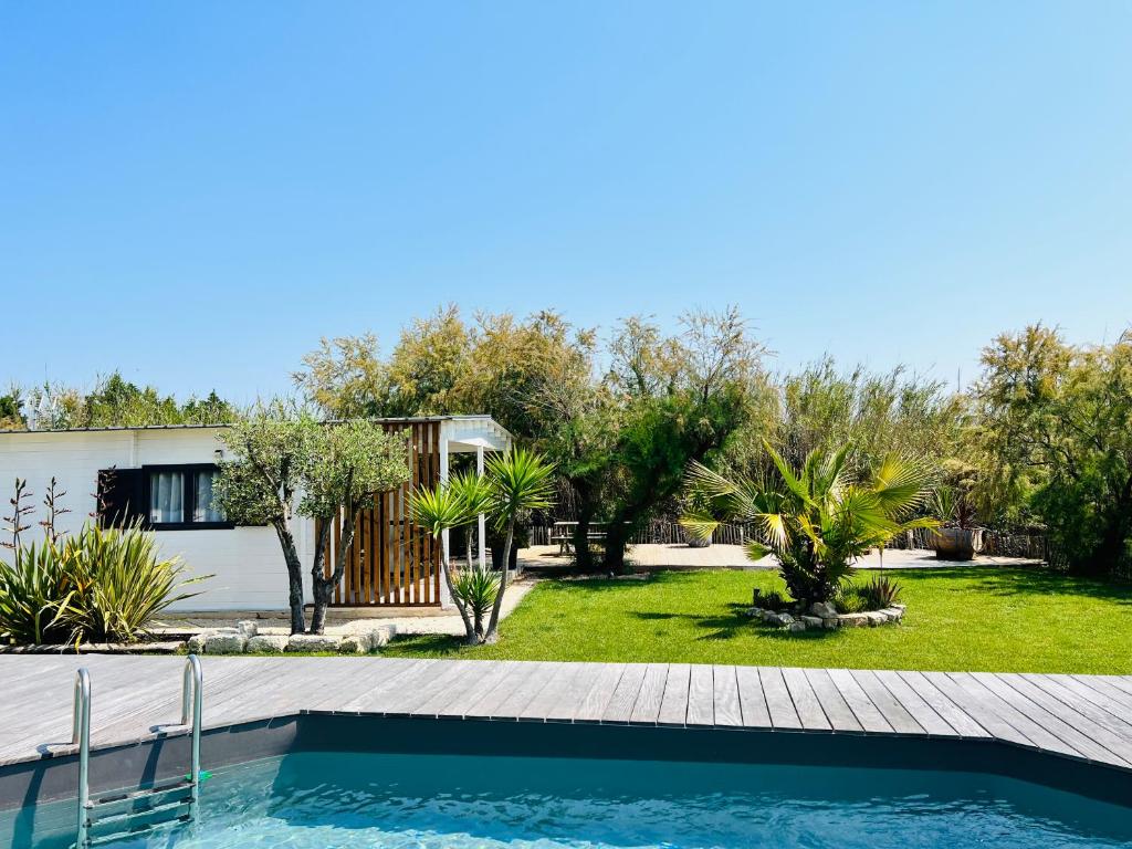 uma casa com uma piscina e um quintal em Cabane le Flamant avec jardin, piscine chauffée et parking em Saintes-Maries-de-la-Mer