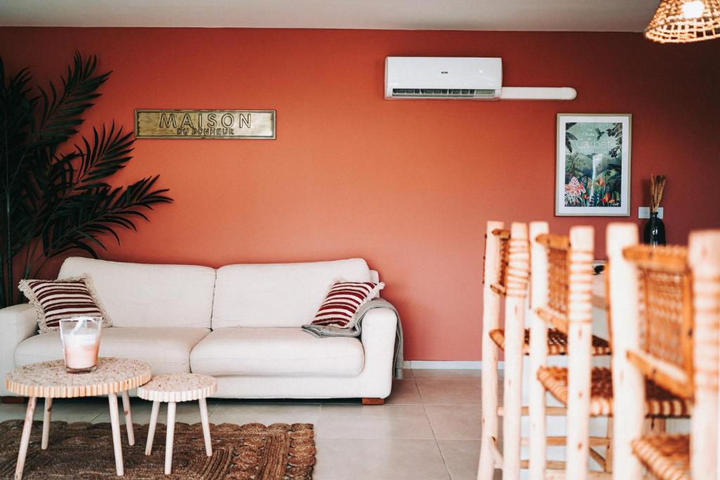 sala de estar con sofá blanco y pared de color naranja en Maloé Lodge T2 (2 min à pieds plage et surf) en Sainte-Anne
