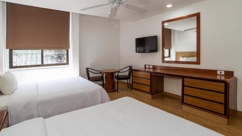 A two-bed bedroom with a compact table, window, and long dresser desk.