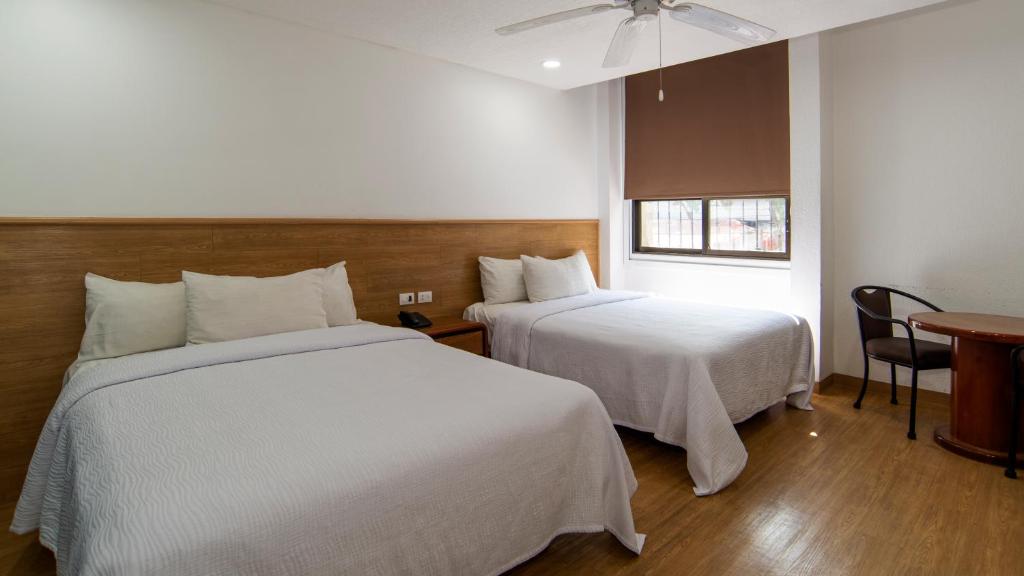 A two-bed room with a small window, table, and chairs.