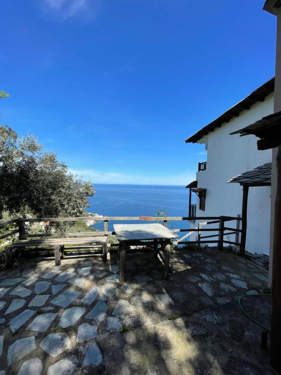 a table and benches on a patio with a view of the ocean at Double studio room with two single beds in Tsagarada