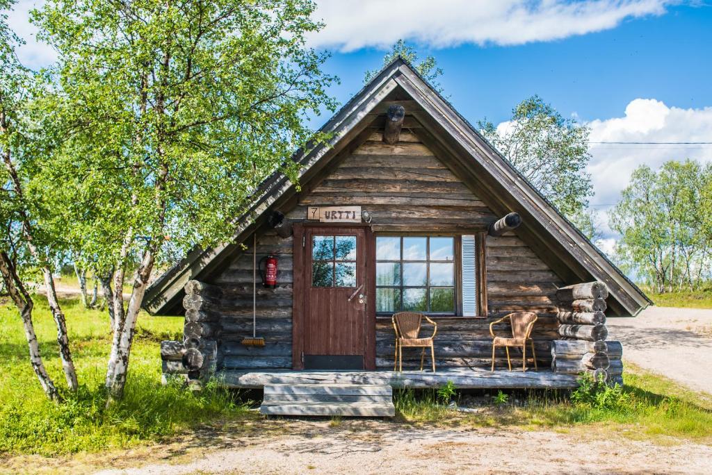 una cabaña de madera con dos sillas delante en Tunturikeskus Galdotieva, en Leppäjärvi