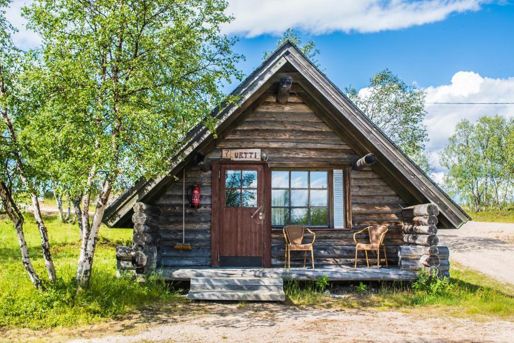 a log cabin with two chairs in front of it at Tunturikeskus Galdotieva in Leppäjärvi