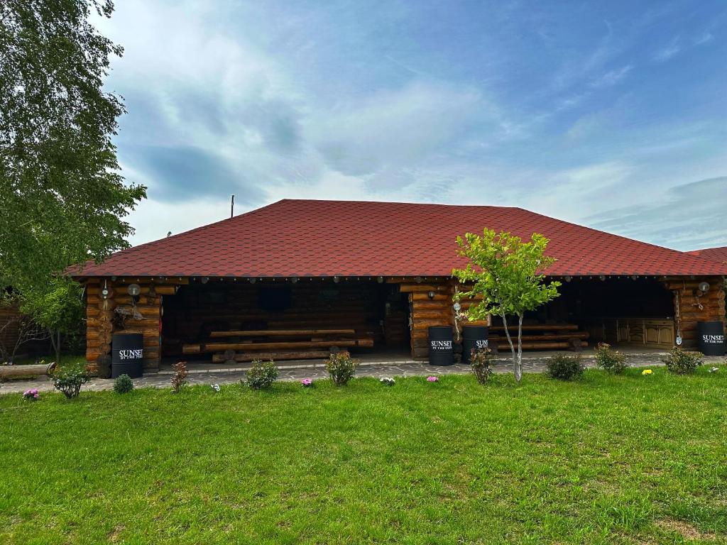 ein Blockhaus mit rotem Dach auf einem Feld in der Unterkunft Sunset By The Farm in Piatra Neamţ