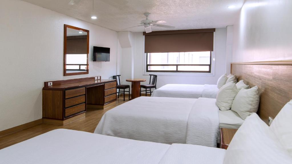 A twin room with two single beds, a dresser, desk-style table, and wide window.