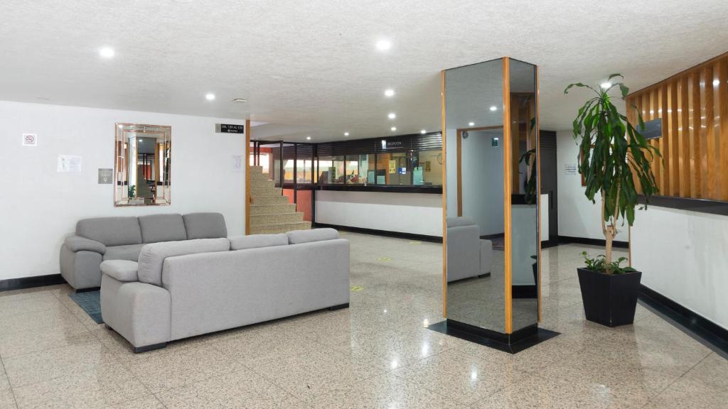 A second view of the lobby with sofas, a mirrored column, and stairs toward reception.