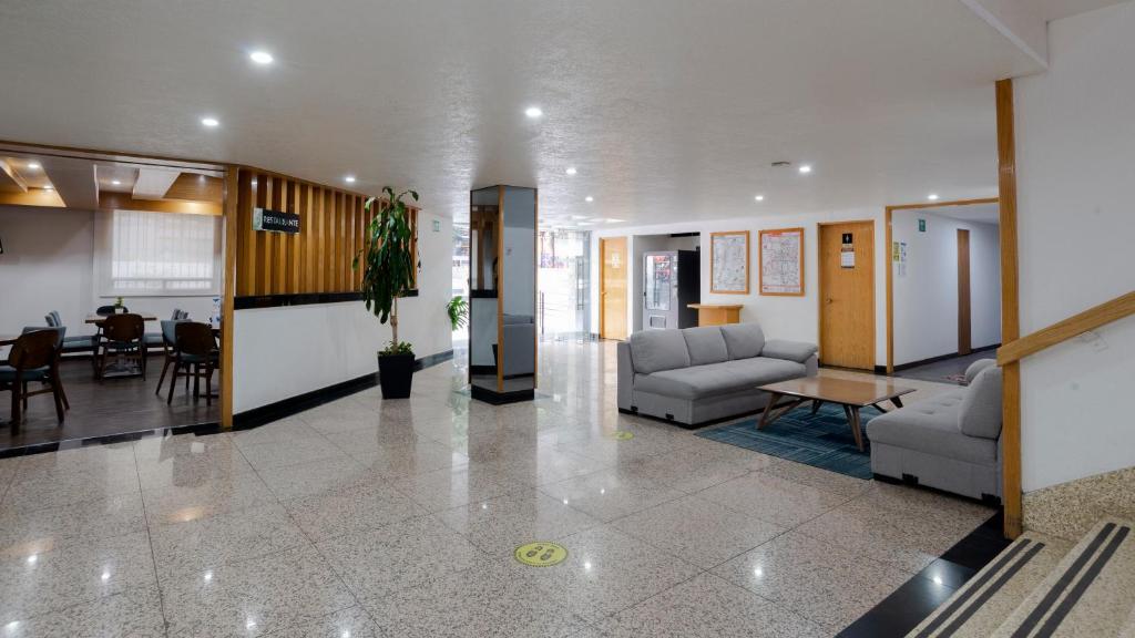A polished entrance lobby with lounge seating, reception, dining tables and a stairway.