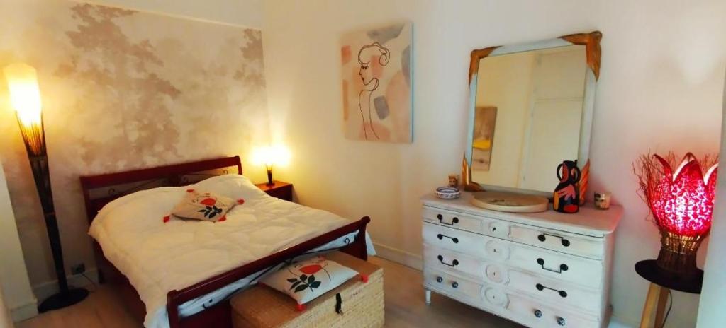 a bedroom with a bed and a dresser and a mirror at LA TERRASSE DE NOTRE DAME in Le Havre