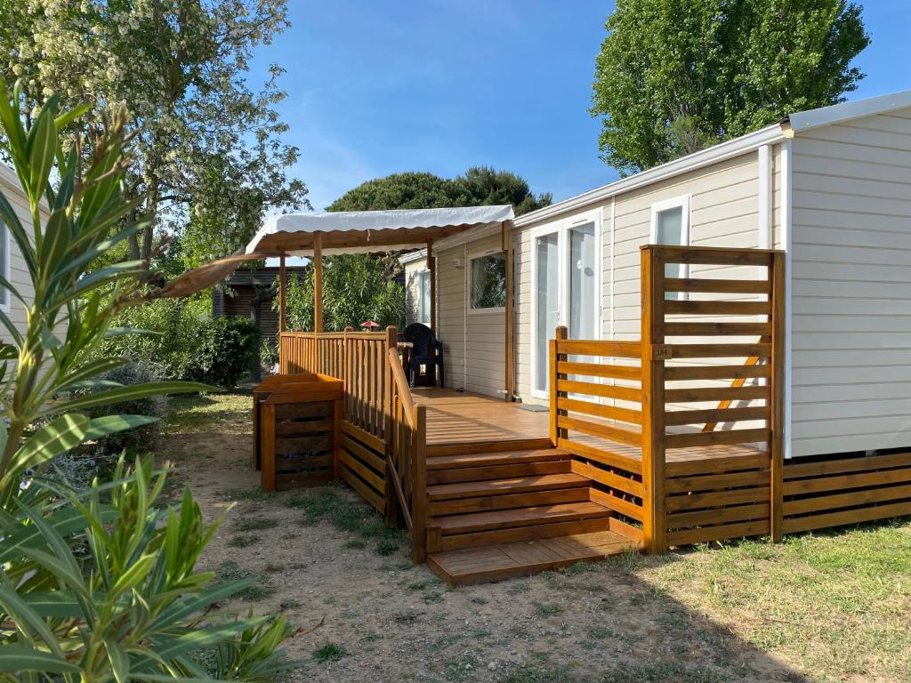 une cabine avec une terrasse en bois à côté d'une maison dans l'établissement Mobil-home Confort TV CLIM Narbonne-Plage, à Narbonne-Plage