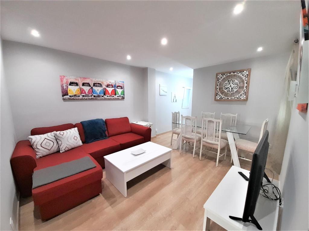 ein Wohnzimmer mit einem roten Sofa und einem Tisch in der Unterkunft Gran apartamento 7 plazas centro de Oviedo-OV4729 in Oviedo
