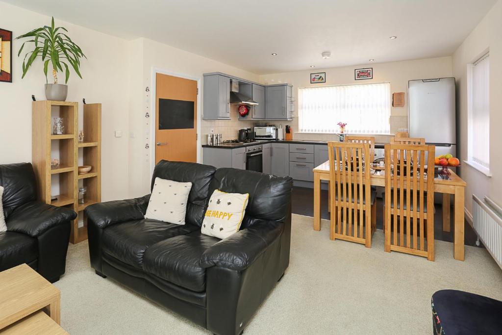 a living room with a leather couch and a kitchen at 3Bed/2Bath Duplex Apartment - Pure Bliss Belfast in Belfast