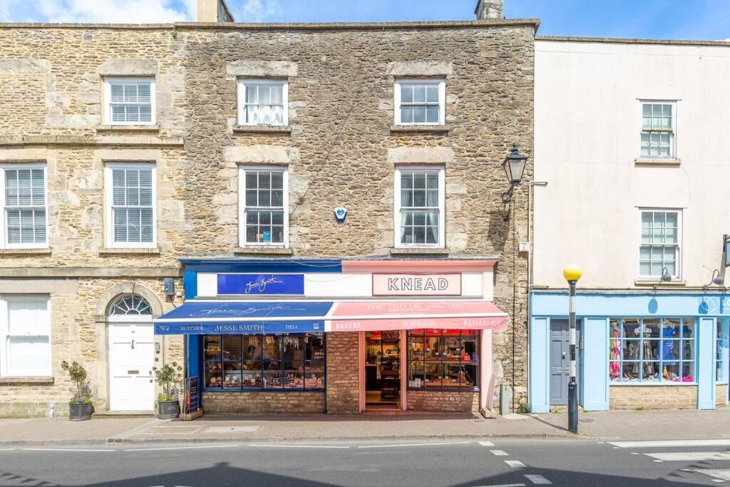 a large brick building with a store on a street at Light and Central Apartment above Knead Bakery in Tetbury