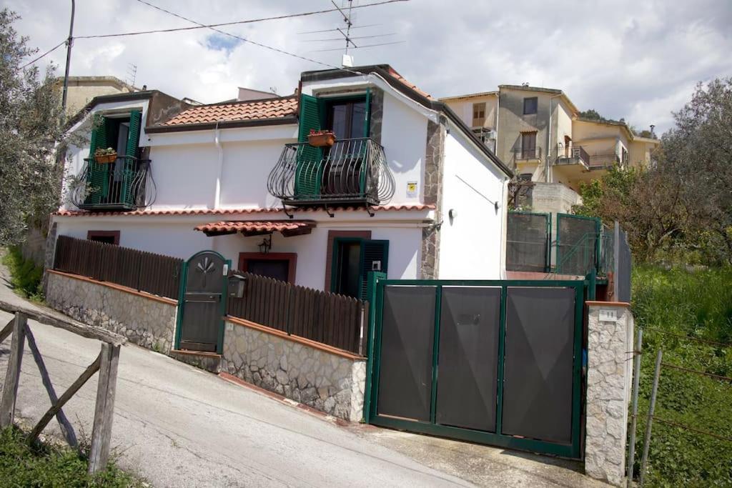 ein weißes Haus mit grünen Türen und einem Zaun in der Unterkunft Casa Salitto San Michele in Olevano sul Tusciano