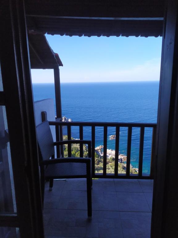 una silla sentada en un balcón con vistas al océano en Double studio room in Mylopotamos with beautifull view, en Tsagkarada