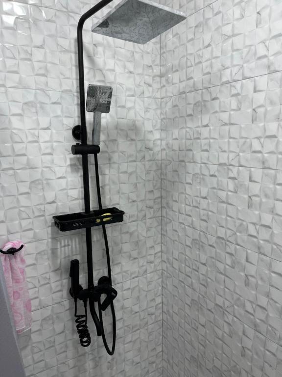 a shower with a phone in a white tiled bathroom at Guest House SAMAN in Garni