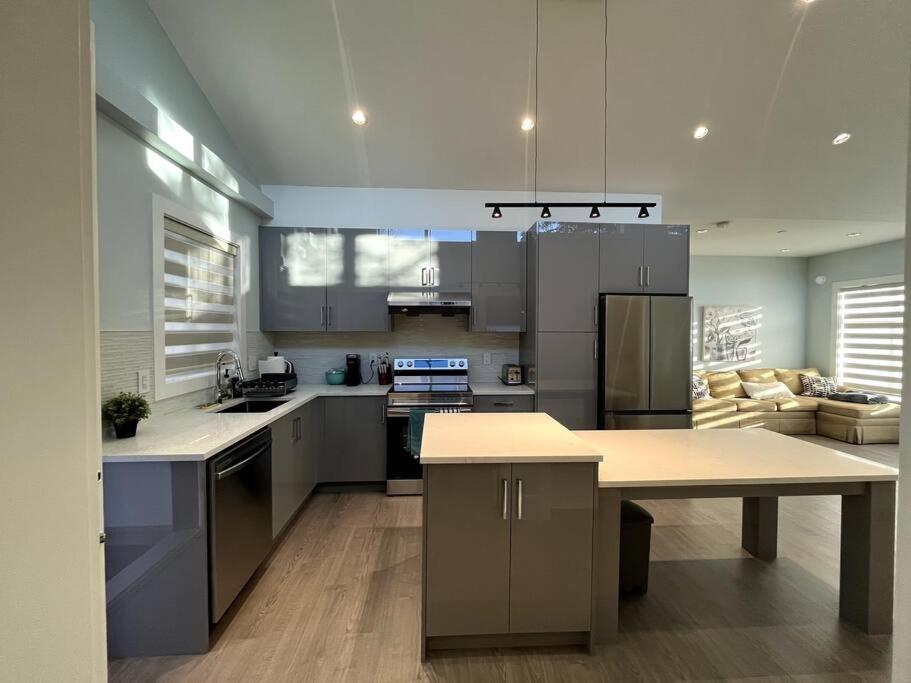 a kitchen with stainless steel appliances and a table at Entire Brand new 3 bed 2 bath Guesthouse in Vancouver