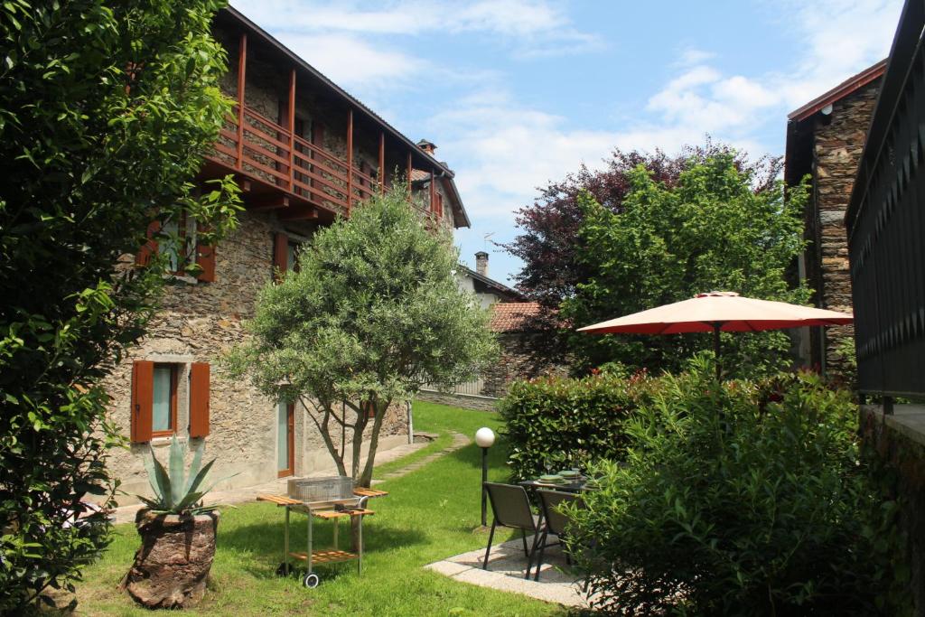 Apartment Bianca with private garden في Cossogno: حديقة فيها طاولة ومظلة ومبنى