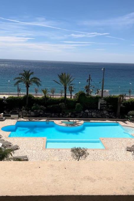 une piscine bleue avec l'océan en arrière-plan dans l'établissement Appartement vue sur mer, à Cannes