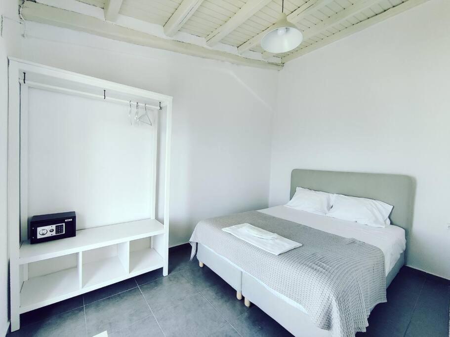 a white bedroom with a bed and a window at Emerald Suite Alonnisos in Patitiri