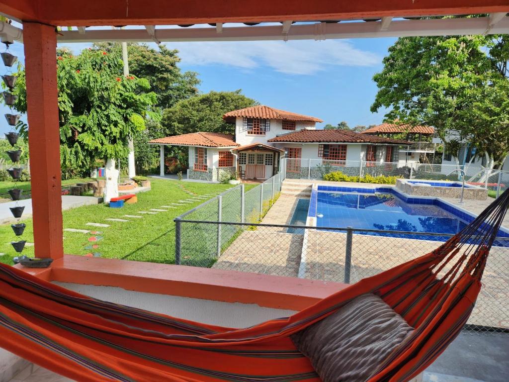 a hammock in front of a house with a pool at Villa Mimosa Finca Hotel in Quimbaya