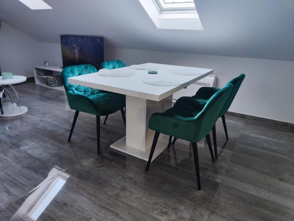 a dining room with a white table and green chairs at Apartment Loft in Sinj