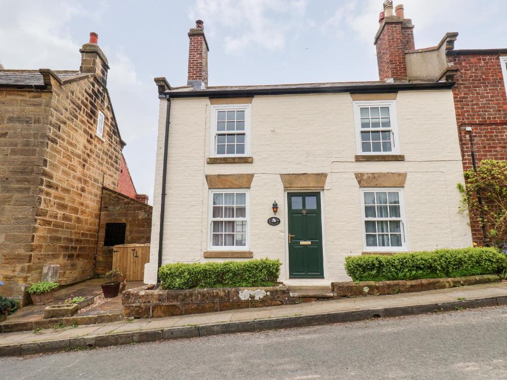 a white house with a green door on a street at Braeside in Whitby