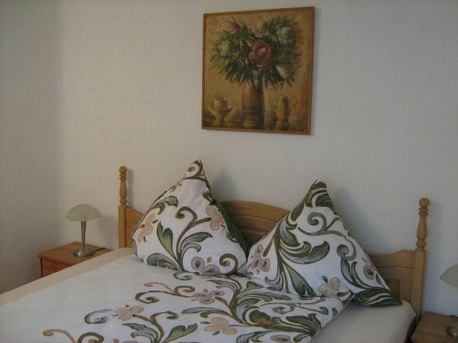ein Bett mit zwei Kissen und einem Gemälde an der Wand in der Unterkunft Ferienhaus im Haus der Künste in Rhodt unter Rietburg