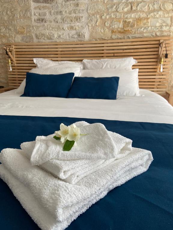 ein Bett mit weißen Handtüchern und einer Blume darauf in der Unterkunft Au cocon de Bélice in Benon