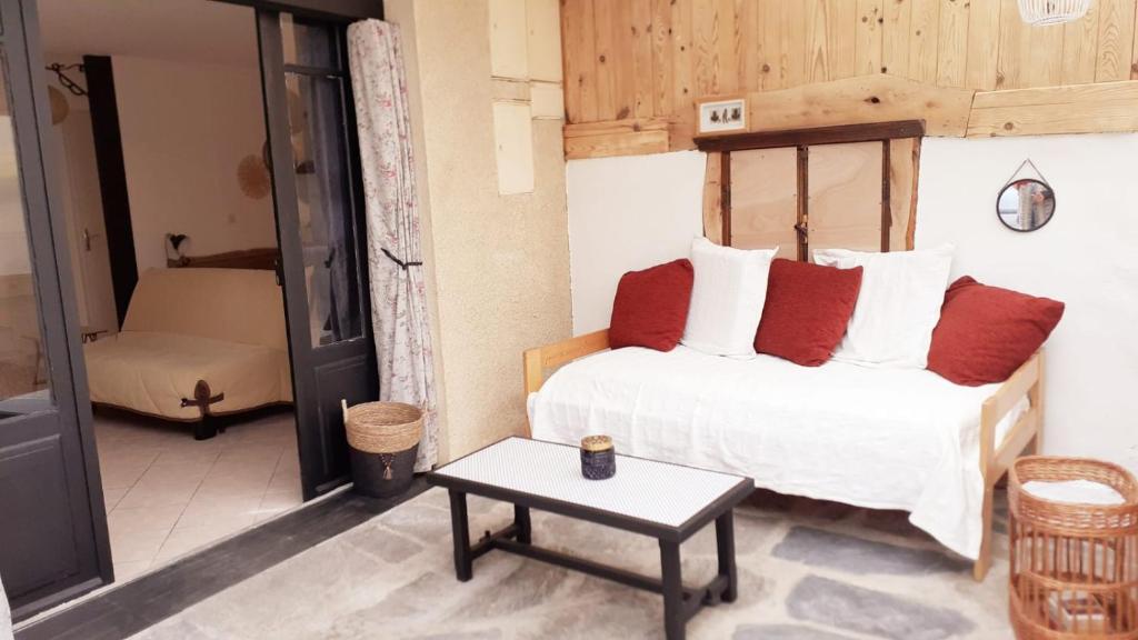 Un dormitorio con una cama con almohadas rojas y una mesa. en Studio au cœur de Laguiole en Laguiole