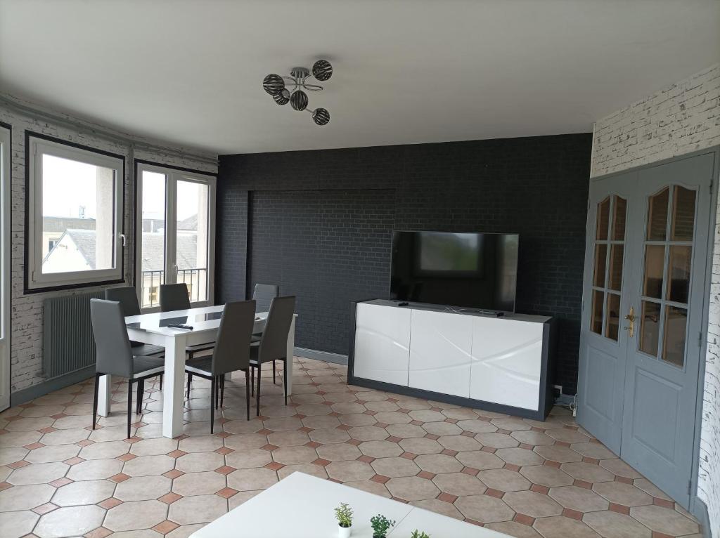 una sala da pranzo con tavolo e TV a schermo piatto di Joli appartement type 5 en centre ville a Châteauroux