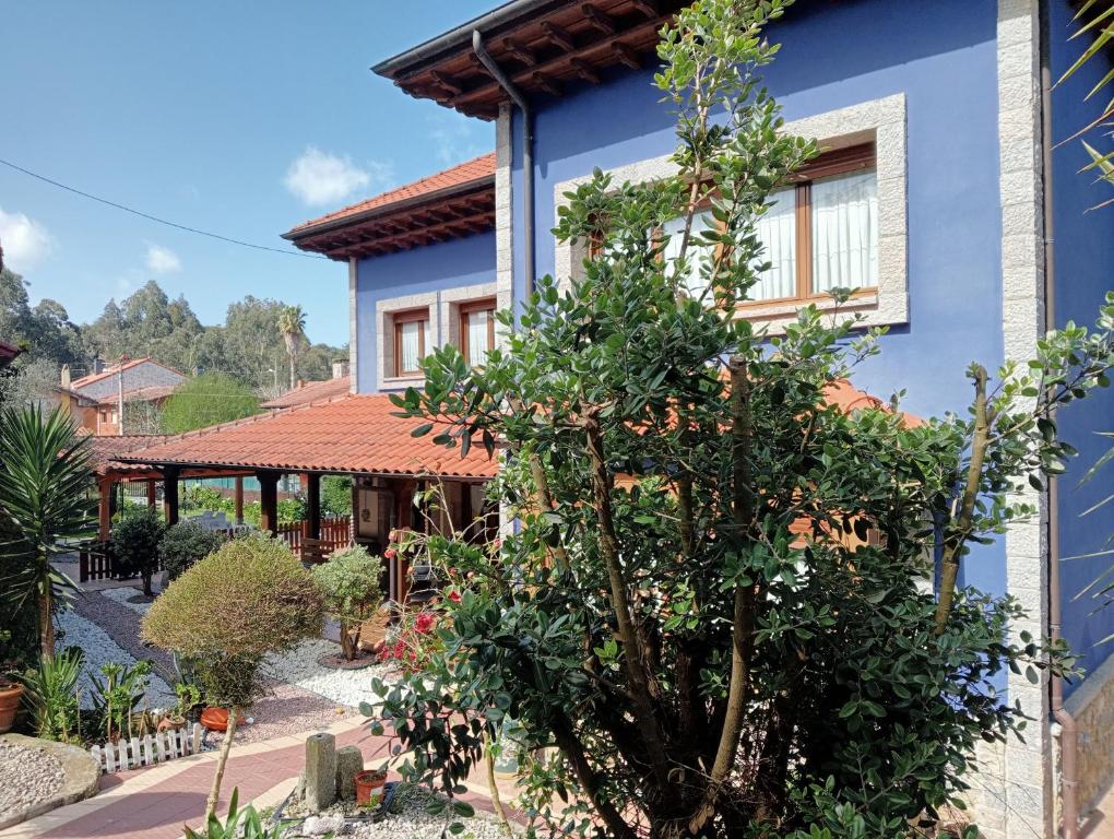 uma casa azul com uma árvore em frente em Marlada Playa de Poo de Llanes em Po