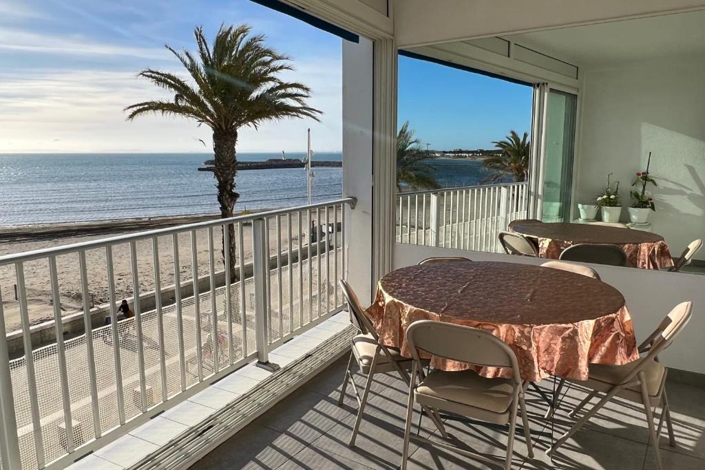 d'un balcon avec deux tables et vue sur la plage. dans l'établissement Mer et Soleil Appartement Vue Mer, au Grau-du-Roi